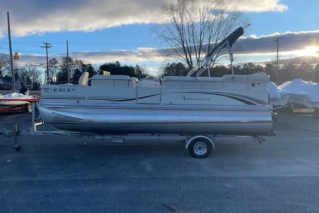 Slide: The Image of 2006 Bennington 2075 GS pontoon boat on trailer, parked outdoors under a cloudy sky. - 3