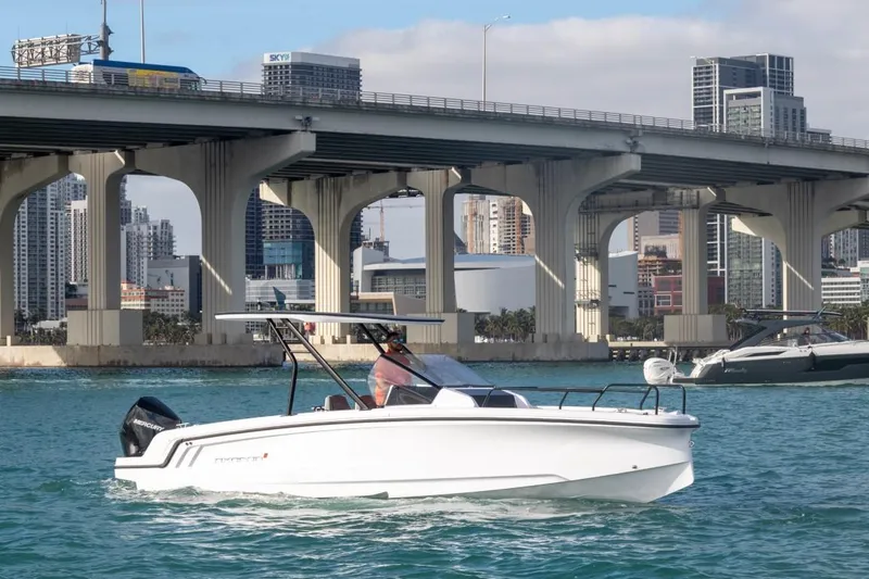 Slide: The Image of 2024 Axopar 25 Cross Top boat cruising under a city bridge. - 1