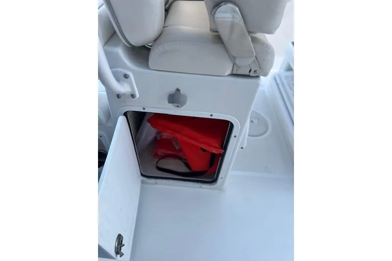 Slide: The Image of 2023 Sea Hunt Ultra 234 boat storage compartment with red life jacket. - 19