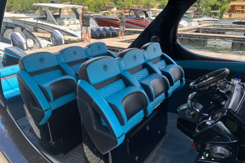 Slide: The Image of Interior of 2023 Mystic Powerboats M4200 with blue and black seating at a marina. - 4
