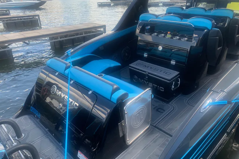 Slide: The Image of 2023 Mystic Powerboats M4200 interior with blue seating and sleek design at a dock. - 6