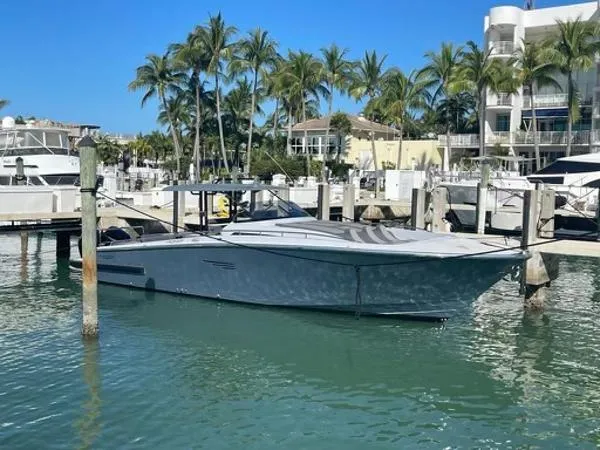 Slide: The Image of 2023 Canados 435 Gladiator yacht docked in a marina with palm trees and clear skies. - 2