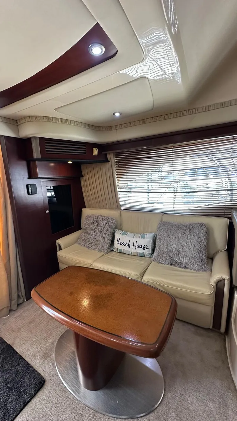 Slide: The Image of Interior of 2006 Sea Ray 44 Sedan Bridge with sofa, table, and "Beach House" pillow. - 13