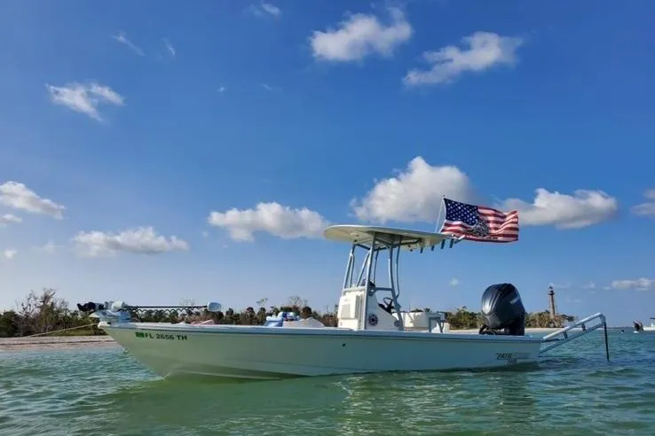 The Image of 2022 Pathfinder 2400 TRS boat with American flag on calm water under blue sky. - 1