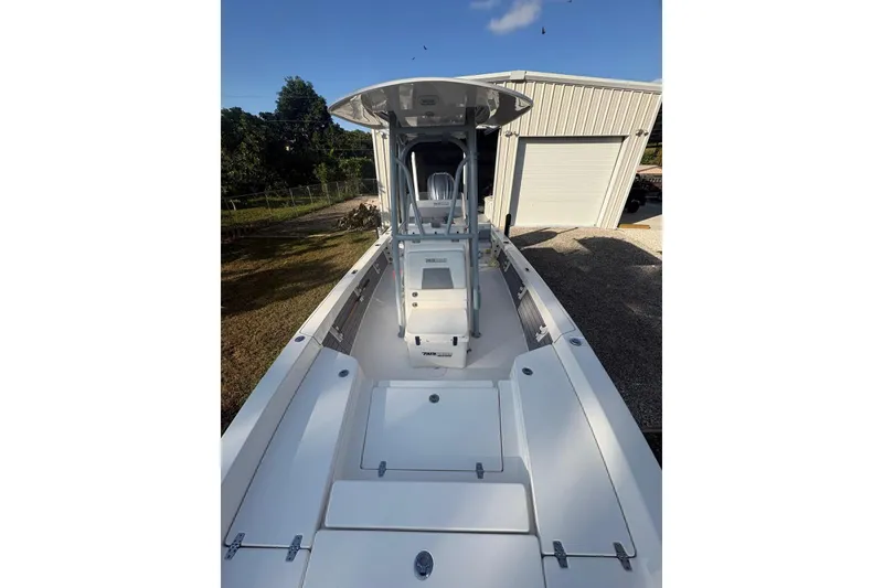 Slide: The Image of 2022 Pathfinder 2400 TRS boat, white deck, parked near a garage. - 13