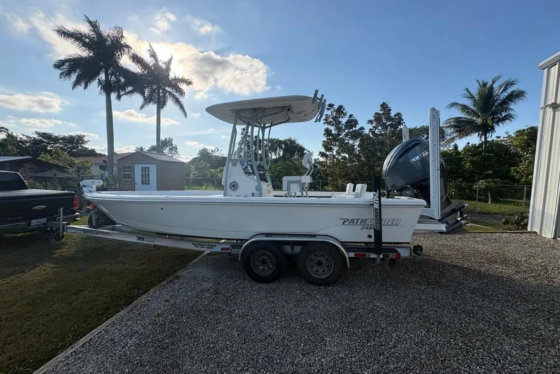 Slide: The Image of 2022 Pathfinder 2400 TRS boat on trailer, parked outdoors with palm trees. - 17