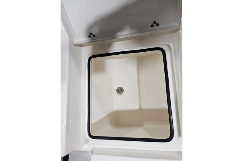 Slide: The Image of 2022 Pathfinder 2400 TRS boat storage compartment with drain, featuring a clean, white interior. - 34