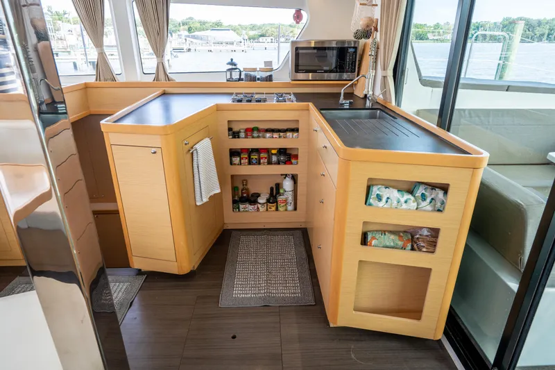 Slide: The Image of Modern kitchen interior on a 2017 Lagoon 42 catamaran, featuring wooden cabinetry and ample storage. - 22