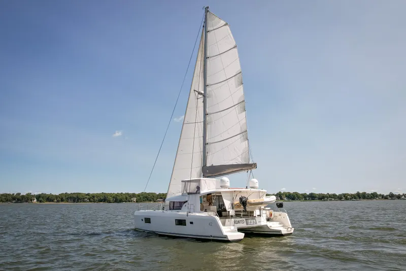 Slide: The Image of 2017 Lagoon 42 catamaran sailing on a calm lake under clear blue skies. - 5