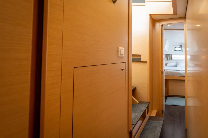 Slide: The Image of Interior hallway of 2017 Lagoon 42 yacht, featuring wooden paneling and a cozy bedroom. - 45