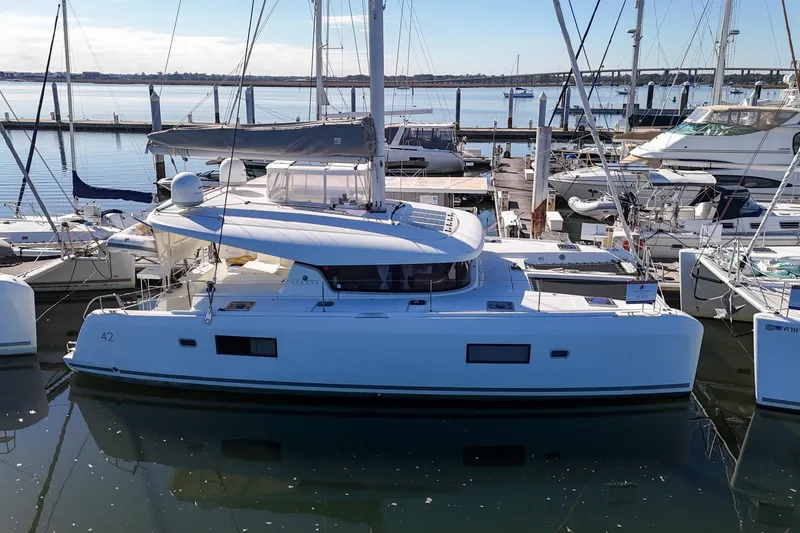 Slide: The Image of 2017 Lagoon 42 catamaran docked at a marina, surrounded by other boats. - 81