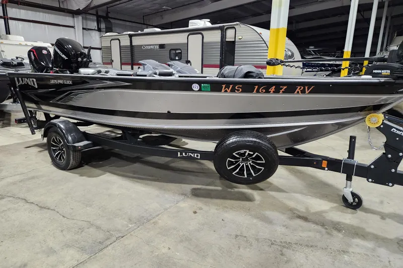 The Image of 2024 Lund 1875 Pro Guide boat on trailer in indoor storage facility. - 0