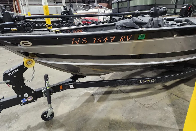 Slide: The Image of 2024 Lund 1875 Pro Guide boat on trailer in warehouse setting. - 2
