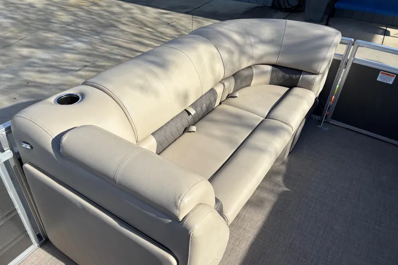 Slide: The Image of 2024 Sun Tracker Party Barge 20 DLX, beige seating with cup holder, outdoor setting. - 12
