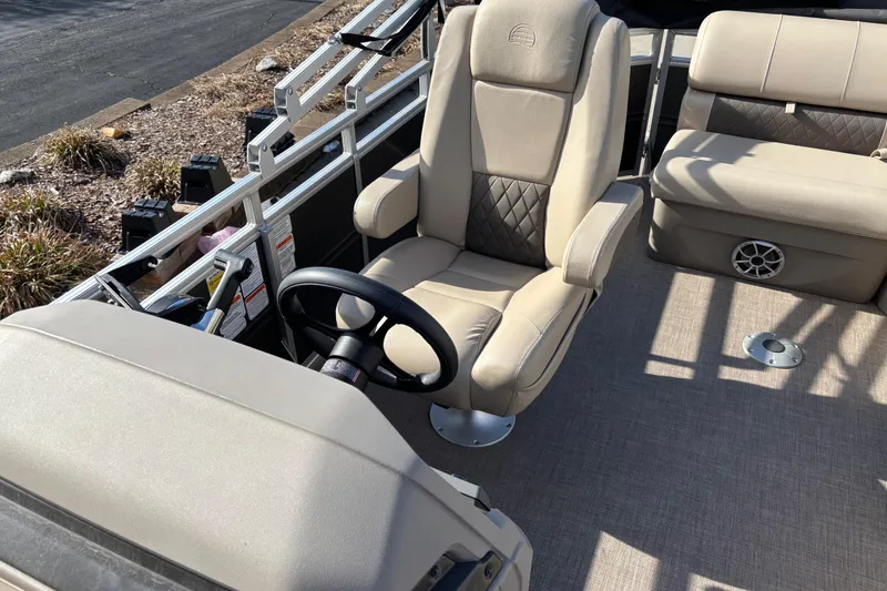 Slide: The Image of 2024 Sun Tracker Party Barge 20 DLX interior with beige seating and steering wheel. - 14