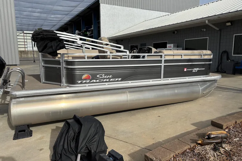Slide: The Image of 2024 Sun Tracker Party Barge 20 DLX pontoon boat parked outside a building. - 2