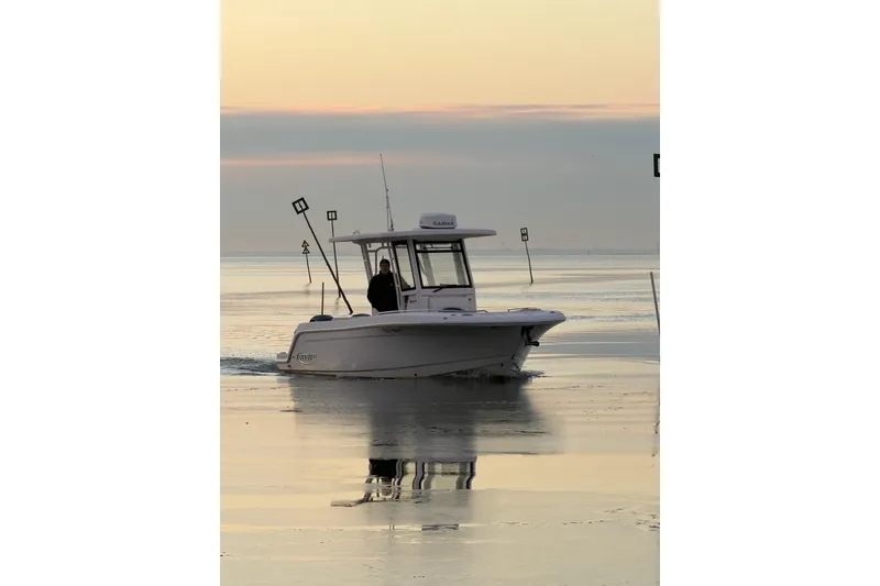 Slide: The Image of 2020 Robalo R272 Center Console boat cruising on calm water at sunset. - 23