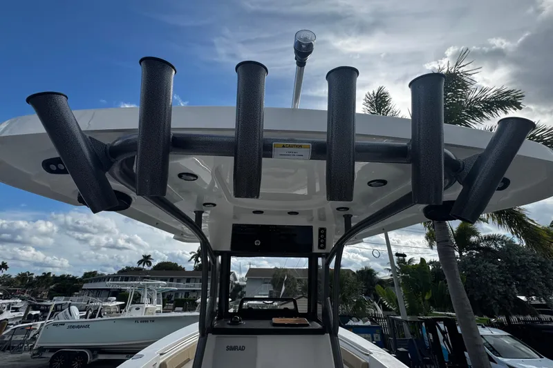 Slide: The Image of 2026 Sea Pro 262 Offshore boat with rod holders and canopy, docked under a cloudy sky. - 19