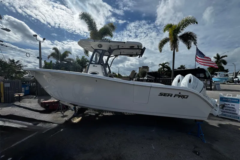 Slide: The Image of 2026 Sea Pro 262 Offshore boat displayed outdoors with palm trees and American flag. - 4
