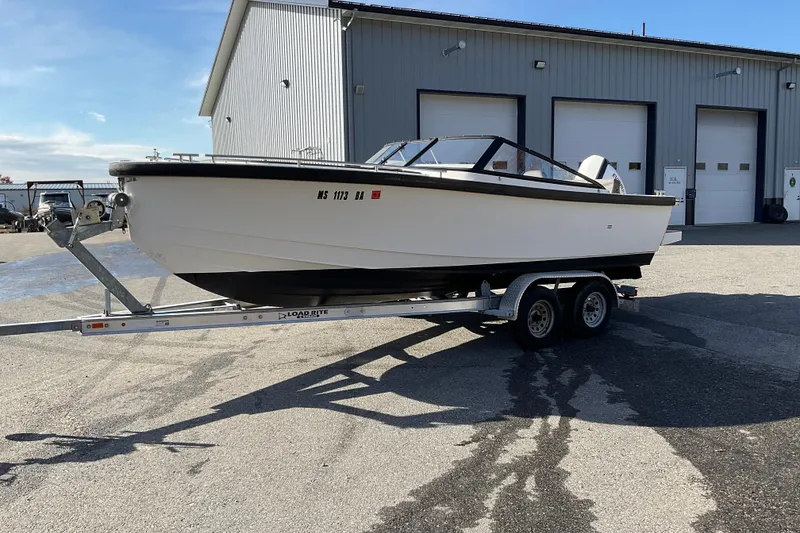 Slide: The Image of 2017 Draco 22RS boat on trailer, parked outside a large industrial building. - 11