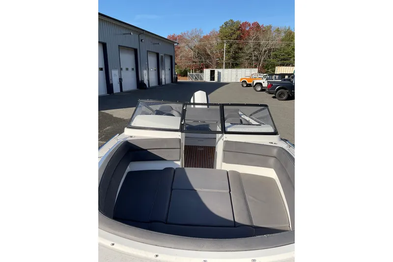 Slide: The Image of 2017 Draco 22RS boat interior with gray seating, parked near a garage. - 12