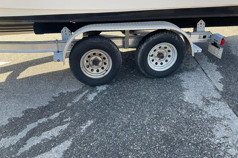 Slide: The Image of Trailer with dual wheels for Draco 22RS boat, 2017 model, on asphalt surface. - 20