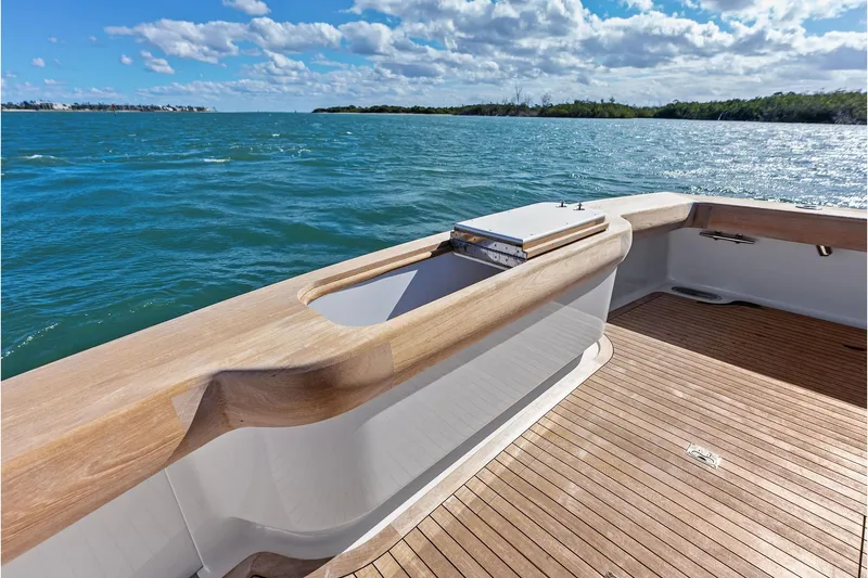 Slide: The Image of 2017 Spencer Convertible boat deck with wooden finish, overlooking serene blue waters. - 26