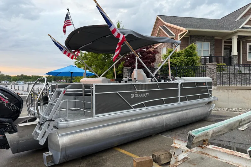 The Image of 2019 Sweetwater 2286 SFL pontoon boat docked with flags and canopy. - 0
