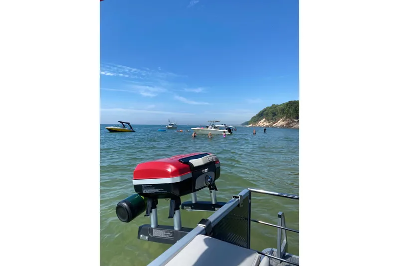 Slide: The Image of 2019 Sweetwater 2286 SFL on scenic lake with boats and swimmers nearby. - 10