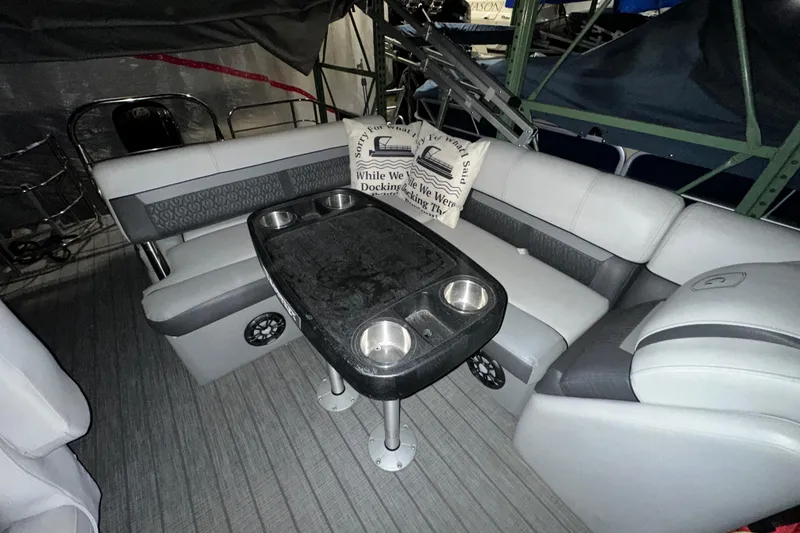 Slide: The Image of 2019 Sweetwater 2286 SFL boat interior with cushioned seating and table with cup holders. - 5