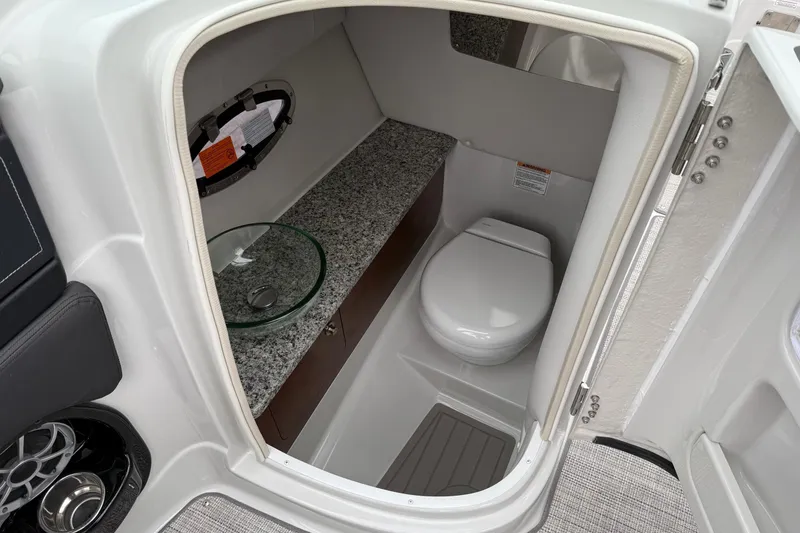 Slide: The Image of 2026 Crownline 288 SS boat interior with modern bathroom, featuring granite countertop and compact toilet. - 10