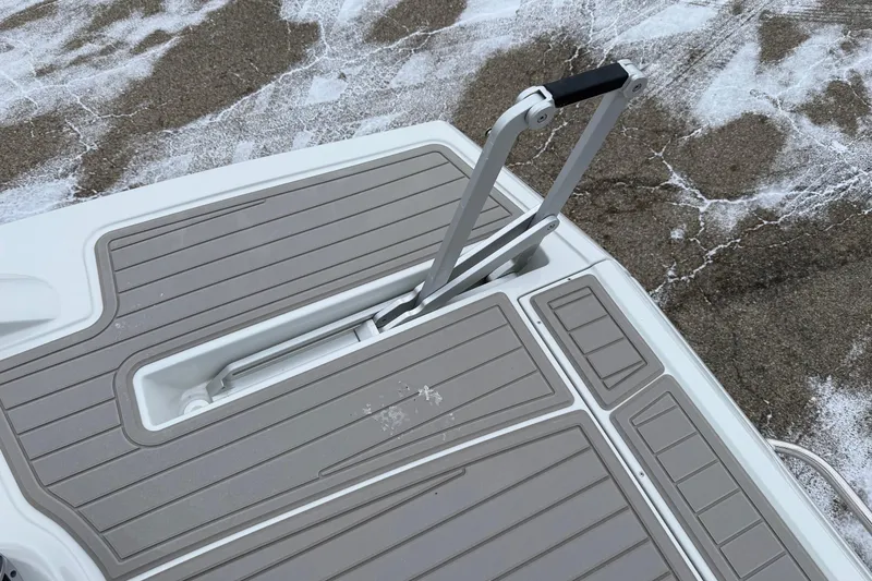Slide: The Image of 2026 Crownline 288 SS boat swim platform with foldable ladder on textured surface. - 3