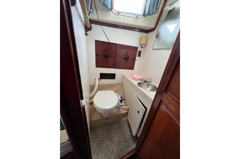 Slide: The Image of 1973 Gulfstar 41 Ketch CC bathroom with toilet, sink, and wooden cabinetry. - 38