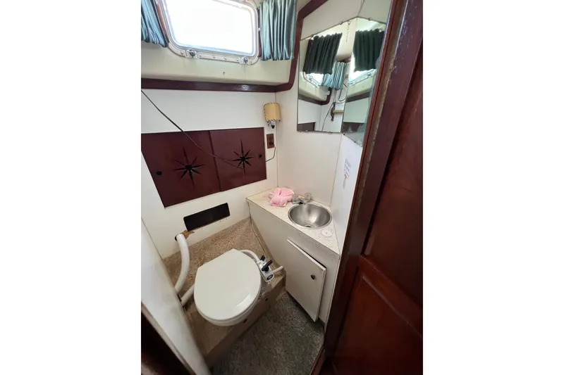 Slide: The Image of 1973 Gulfstar 41 Ketch CC bathroom with toilet, sink, mirror, and window. - 44