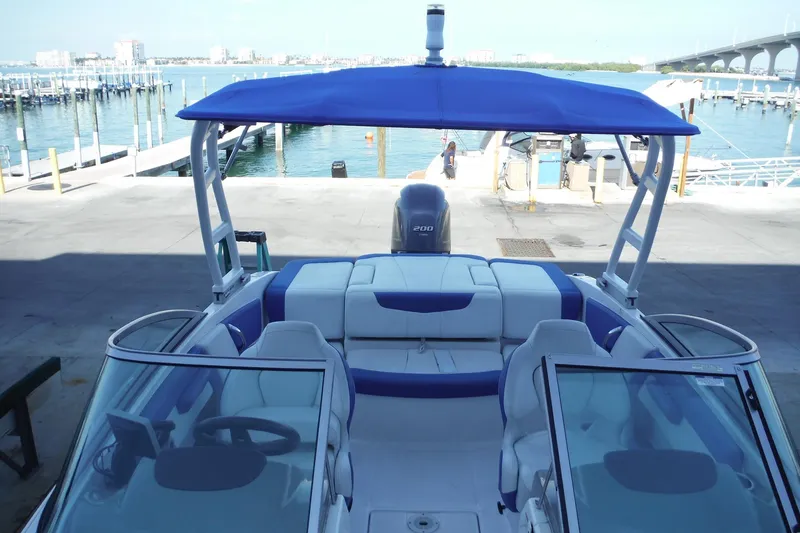 Slide: The Image of 2018 Chaparral 21 H2O Sport OB boat docked with blue canopy and waterfront view. - 29