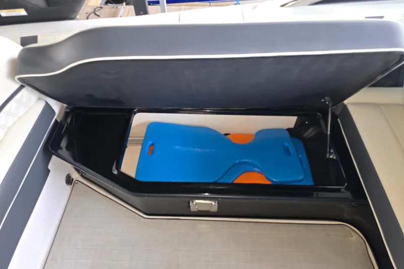 Slide: The Image of 2021 Regal 2800 Bowrider storage compartment with blue and orange accessories. - 25