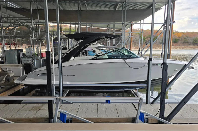 Slide: The Image of 2021 Regal 2800 Bowrider boat docked in a marina, surrounded by water and autumn trees. - 4