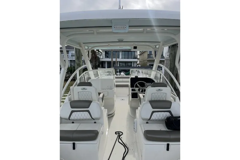 Slide: The Image of 2022 World Cat 255 DC boat interior with seating and steering wheel, docked near waterfront homes. - 11
