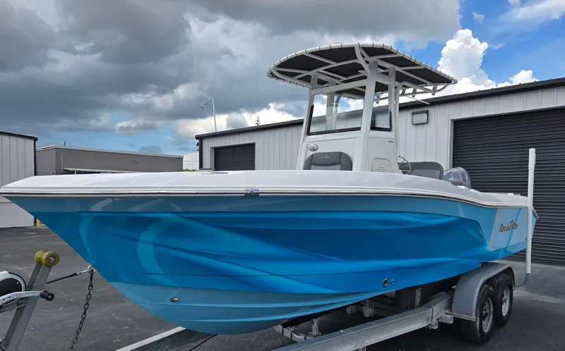 The Image of 2023 NauticStar 242L Offshore boat on trailer, blue hull, parked outdoors. - 1