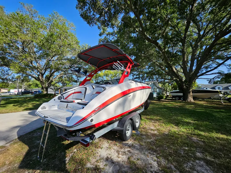 Slide: The Image of 2020 Yamaha Boats 242X on trailer, parked outdoors under trees. - 3