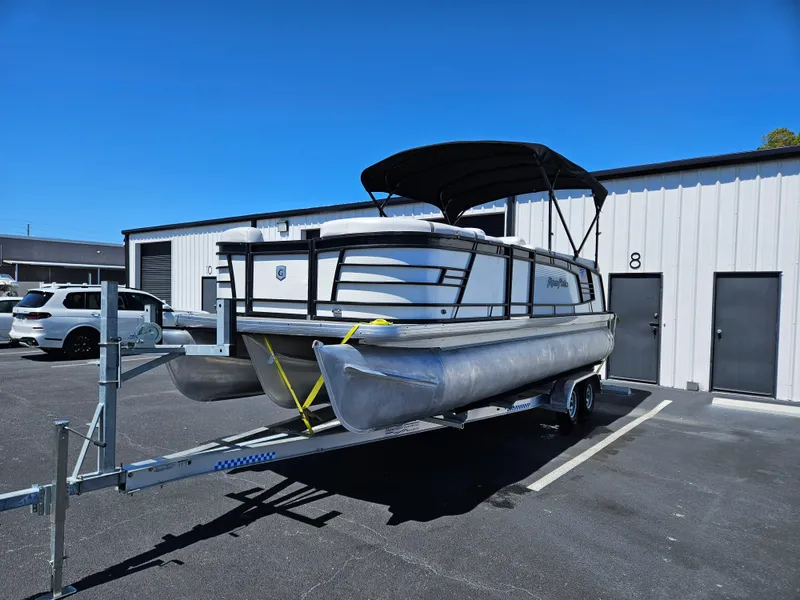 The Image of 2017 Godfrey AquaPatio 235 SB pontoon boat on a trailer in a parking lot. - 0