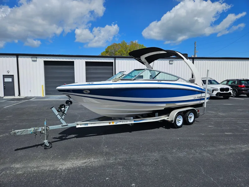 The Image of 2014 Regal 2100 Bowrider boat on trailer in parking lot. - 1