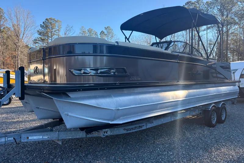 Slide: The Image of 2022 Avalon Excalibur Elite Windshield 27' pontoon boat on trailer, parked outdoors. - 3
