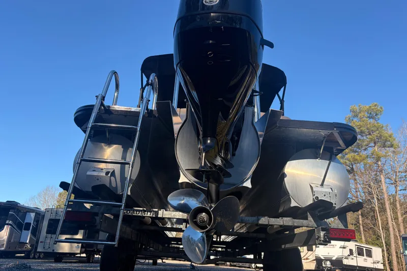 Slide: The Image of 2022 Avalon Excalibur Elite Windshield boat, rear view with ladder and propeller, outdoors. - 5