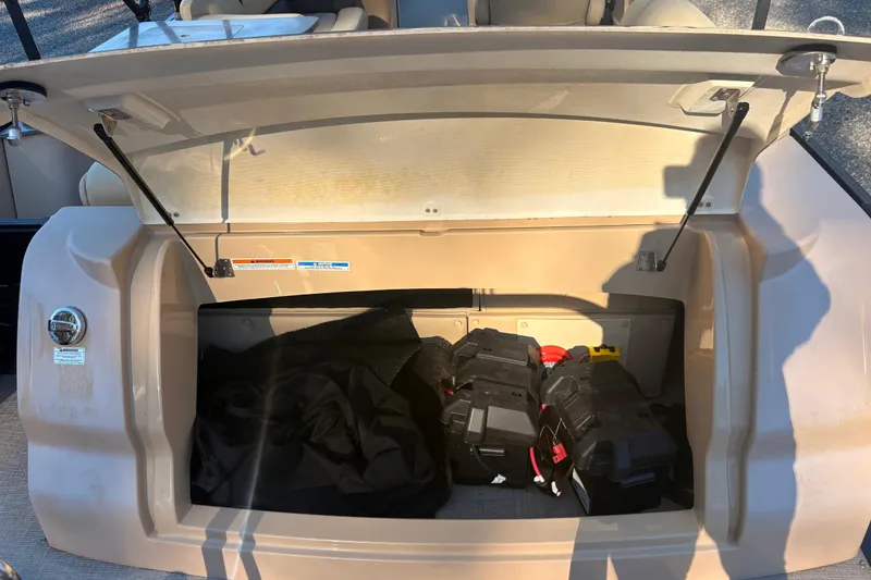 Slide: The Image of Open storage compartment of 2022 Avalon Excalibur Elite Windshield boat, showing battery and equipment. - 9