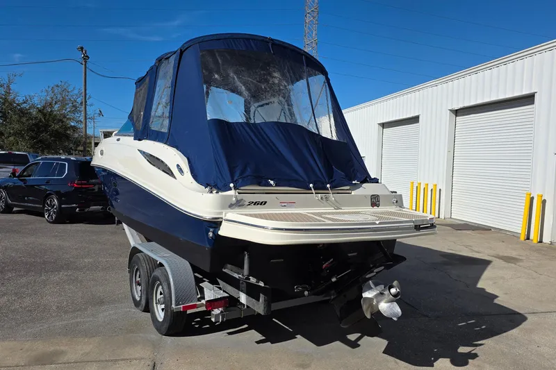 Slide: The Image of 2010 Sea Ray 260 Sundeck boat on trailer, covered, parked near a building. - 16