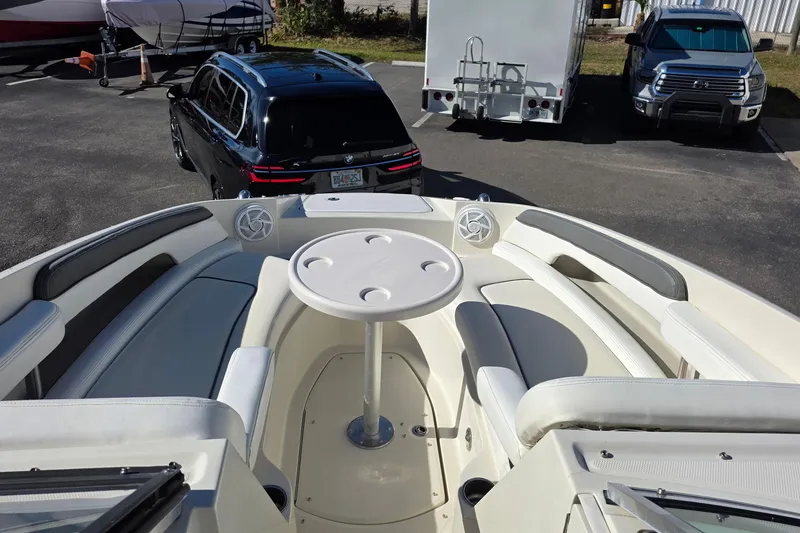 Slide: The Image of 2010 Sea Ray 260 Sundeck boat interior with seating and table, parked near vehicles. - 33