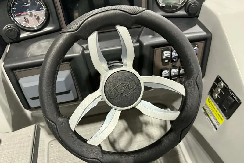 Slide: The Image of Steering wheel of 2026 Manitou Encore SL 230 SHP boat, featuring modern dashboard controls. - 13