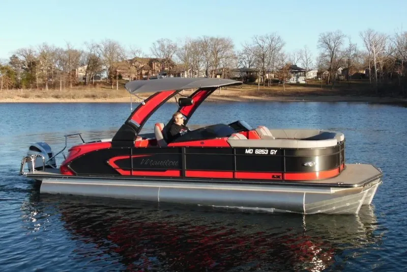 The Image of 2023 Manitou 25 XT RFX pontoon boat on a calm lake. - 0