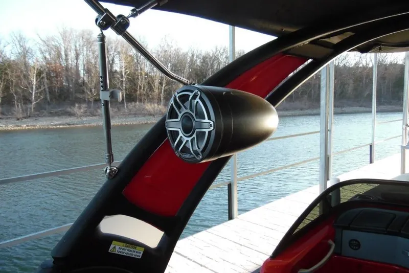 Slide: The Image of 2023 Manitou 25 XT RFX boat with sleek speaker system on a calm lake. - 22